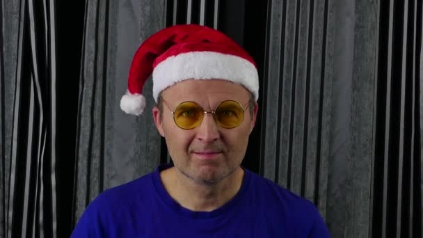 Hombre positivo en Santa Claus sombrero se quita las gafas amarillas. — Vídeo de stock