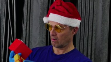 Noel Baba şapkalı bir adam kutudan bir maske çıkarır ve onu takar..