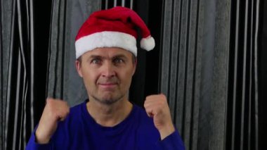  40-55 yaşlarında, Noel Baba şapkası takan ve elleriyle hareket eden çekici bir adam..