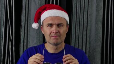 Noel Baba şapkalı adam sarı gözlük takıyor..