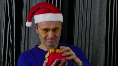 Noel Baba şapkalı neşeli bir adam hediye kutusunu açıyor..