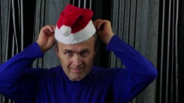 Yakışıklı bir adam Noel Baba şapkası takar ve onaylayıcı bir jest yapar.. 