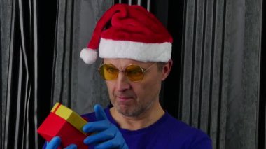 Noel Baba şapkalı adam hediye kutusundan maskeyi çıkardı..