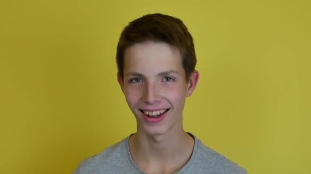 Un ragazzo adolescente sorridente contro uno sfondo giallo studio. — Video Stock