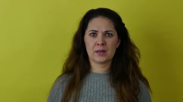 Schöne wütende Frau runzelt die Stirn, während sie vor Wut in die Kamera auf gelbem Hintergrund blickt. — Stockvideo