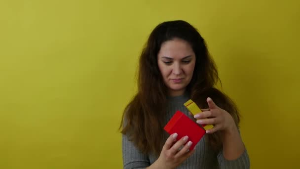 Een mooie vrouw opent een rode feestelijke doos en komt in een staat van verrukking. — Stockvideo