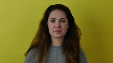Uzun saçlı güzel bir kadın sarı arka planda bir konuşma prova ediyor..