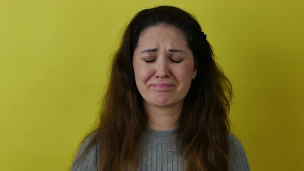 Retrato de una hermosa mujer llorando con el pelo largo sobre un fondo amarillo. — Vídeos de Stock