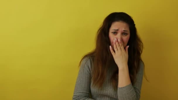 Una hermosa mujer está furiosa con malas noticias sobre un fondo amarillo. — Vídeos de Stock