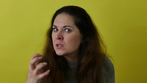 Portret van een boze en verontwaardigde vrouw op een gele achtergrond. — Stockvideo