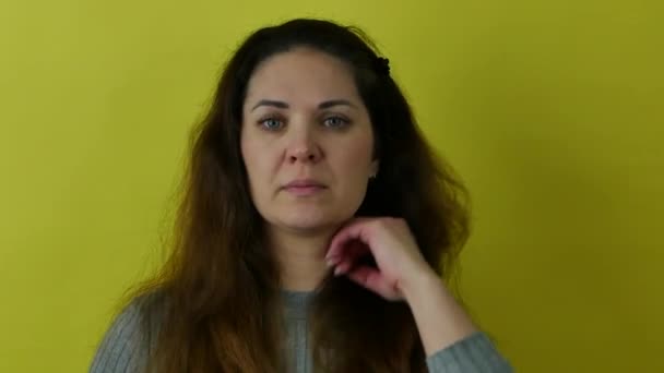A beautiful woman with long hair rehearses a speech on a yellow background. — Stockvideo