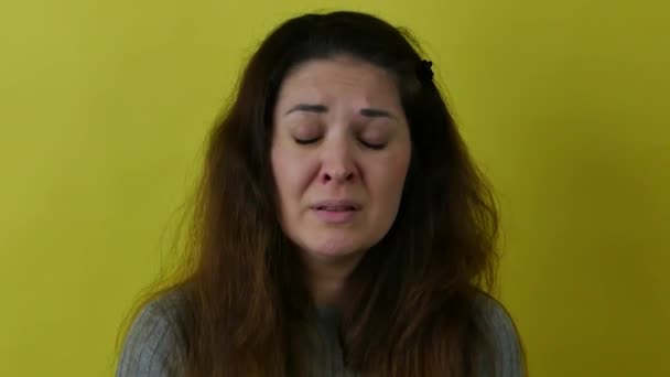 Портрет красивой плачущей женщины с длинными волосами на желтом фоне. — стоковое видео