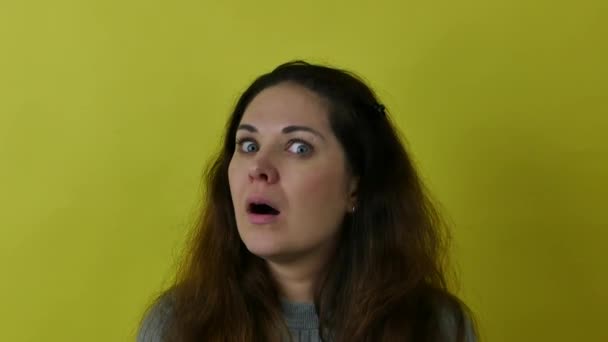Beautiful emotional woman wondering against a yellow background. — Stock Video
