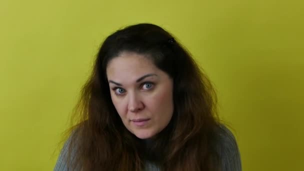 Beautiful emotional woman wondering against a yellow background. — Wideo stockowe