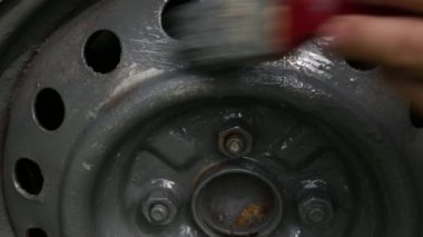 El boyası araba tekerlekleri, araba bakımı. Kırpılmış bir adamın elleri tekerlek kenarını gri boyayla boyuyor. Yüksek kaliteli FullHD görüntüler