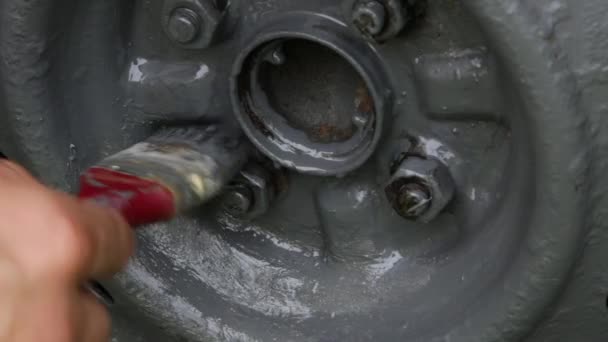 A hand with a red paintbrush paints a disc from a car wheel with gray paint. — Stock Video
