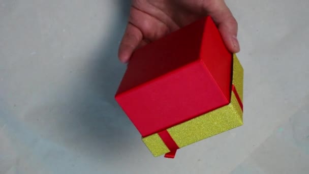 Man hand hålla en röd och gul presentförpackning. — Stockvideo
