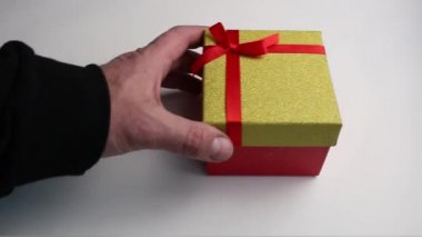  Erkek eli beyaz arkaplana kırmızı ve mavi hediye kutuları koyar.