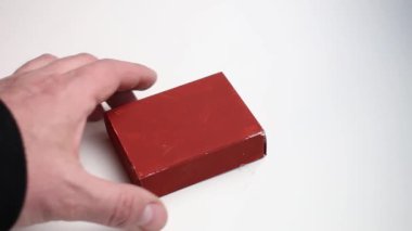 Mans el beyaz arkaplandan kırmızı kutuyu alır.