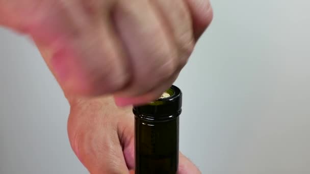 Mannelijke hand opent een fles wijn met een kurkentrekker op een lichte achtergrond.. — Stockvideo