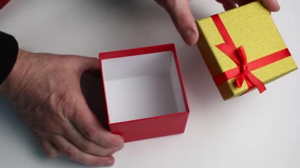 Las manos abren una caja de regalo y le ponen un regalo. — Vídeo de stock