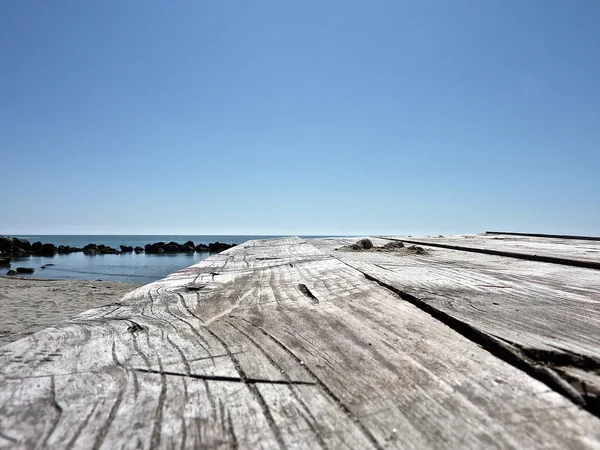 Alter Holztisch am Strand verlassen — Stockfoto