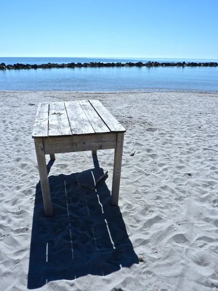 Alter Holztisch am Strand verlassen — Stockfoto