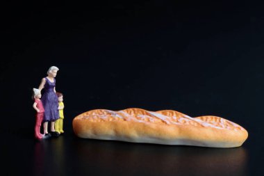 Oğulları ve siyah arka planda ekmeği olan bir annenin minyatür biblosu.