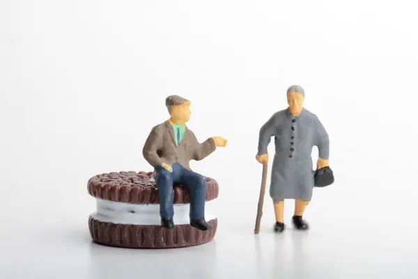 miniature figure of a man and a woman with a cake on white background.