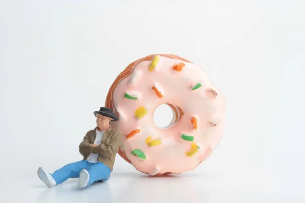 miniature figurine of a sleeping man  with a huge donut on white background