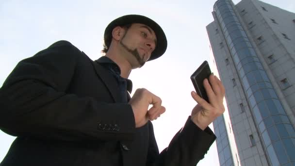 Businessman gesturing on touchscreen smartphone in front of office building — Stock Video