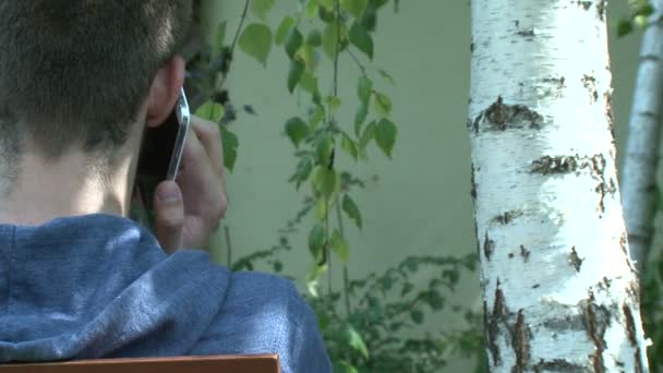 Eco concept - Teenager laden Smartphone vom Baum — Stockvideo