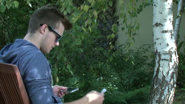 Eco concept - Teenager laden Smartphone vom Baum — Stockvideo