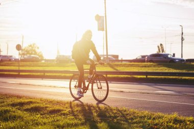 Riga, Letonya - 6 Ekim 2021: İnsanlar, seyahat, turizm, eğlence ve yaşam tarzı - sabit vitesli bisiklet ve sırt çantalı mutlu genç hippi, şehir caddesinde güneş etkisi