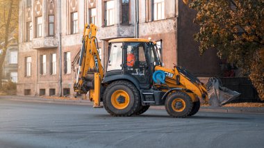 Riga, Letonya-6 Ekim 2021: Sarı JCB inşaat traktörü bir sonbahar sabahı şehir caddesinde sürüyor