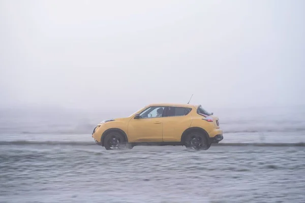 Riga, Letonya - 15 Kasım 2021: Sarı Nissan Juke sisli sonbahar sabahında sürüyor, hareket bulanık arkaplan