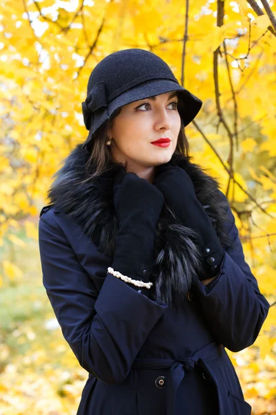 Γυναίκα σε ένα μαύρο καπέλο σε φόντο του φθινοπώρου δέντρο — Φωτογραφία Αρχείου