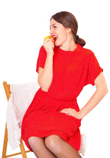 Žena jíst jablko sedící na židli — Stock fotografie