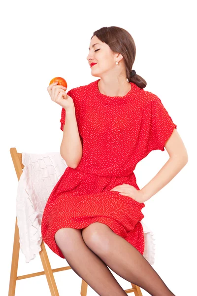 Woman holding an apple sitting on a chair — Stock Photo, Image