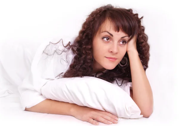 Beyaz gömlekli bir yatakta yatarken güzel genç kadın — Stok fotoğraf