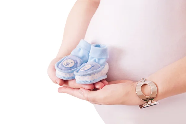 赤ちゃんのための青い靴のペアを保持している妊娠中の女性 — ストック写真