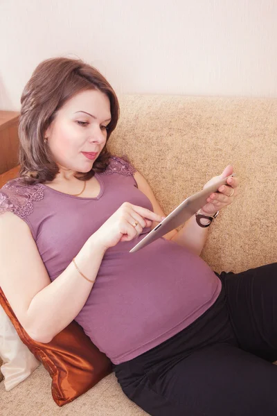 Gelukkig zwangere vrouw met behulp van een digitale tablet — Stockfoto