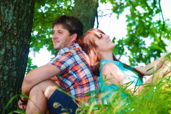 Smilende par hviler nær et træ - Stock-foto