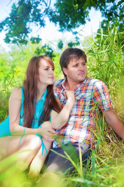 Smiling couple resting near a tree — Stock Photo, Image