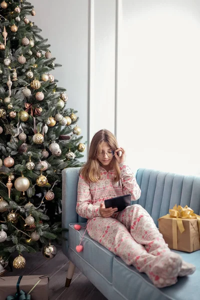 Ragazza adolescente con un tablet vicino a un albero di Capodanno o in un interno di Natale. — Foto Stock
