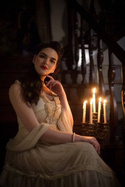İç mekânında mumları olan klasik elbiseli bir kadın. Retro tarzı veya tiyatro.