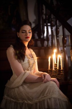 İç mekânında mumları olan klasik elbiseli bir kadın. Retro tarzı veya tiyatro.