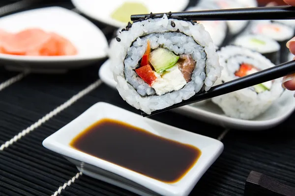 Hand holding sushi on sticks — Stock Photo, Image