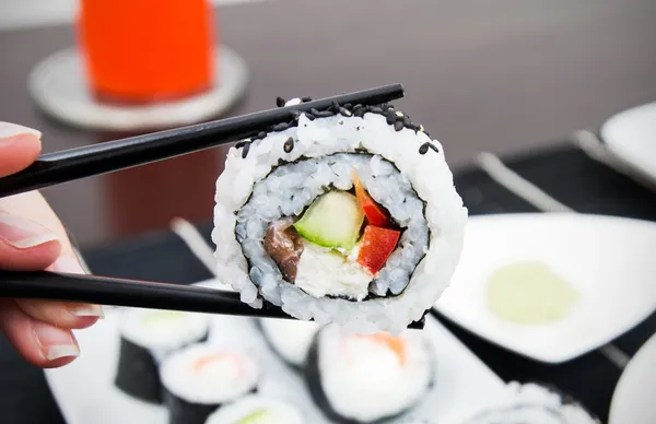 Hand holding sushi on sticks — Stock Photo, Image