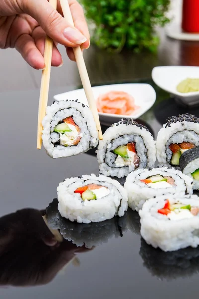 Hand holding stick with maki sushi set — Stock Photo, Image